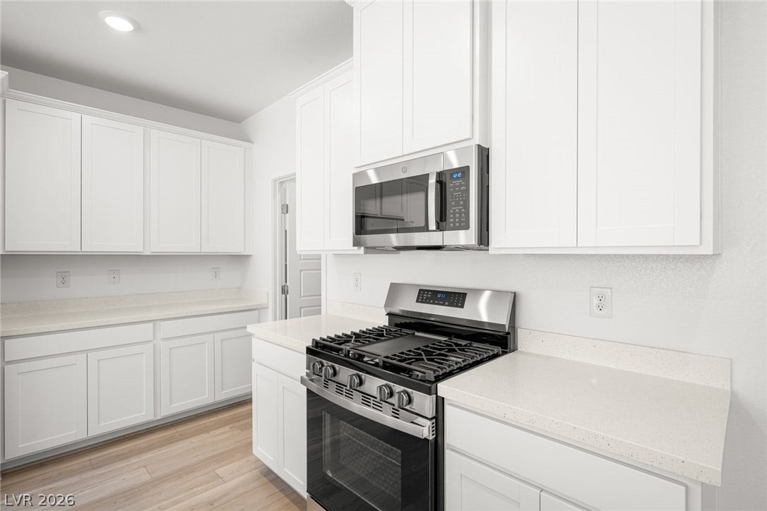 1429 Bianca Falls Drive, Henderson, NV 89011 Crisp white cabinetry pairs with quartz countertops and stainless steel appliances in this kitchen.