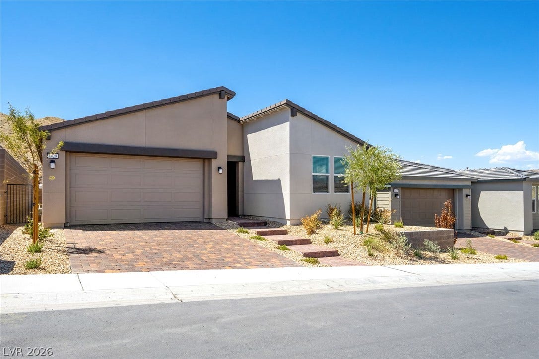 1429 Bianca Falls Drive, Henderson, NV 89011 Modern desert architecture defines this single-story home featuring a paved driveway and clean exterior lines.