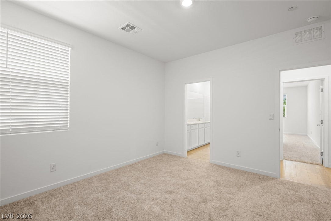 1429 Bianca Falls Drive, Henderson, NV 89011 Plush carpeting anchors this spacious bedroom featuring clean lines and direct bathroom access.