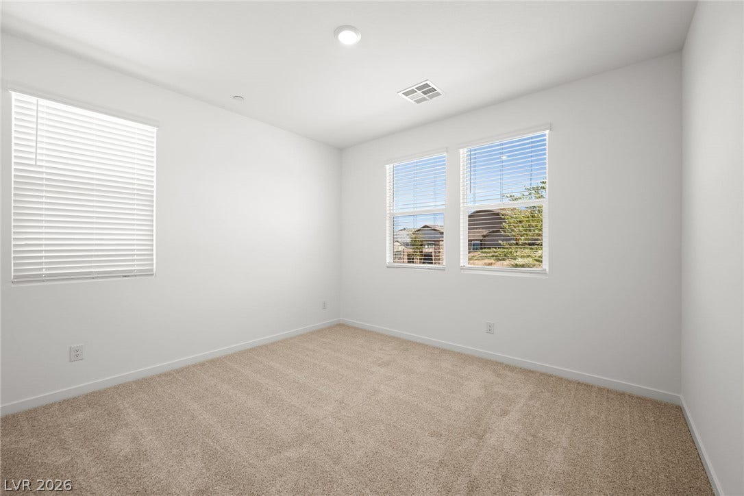 1429 Bianca Falls Drive, Henderson, NV 89011 Plush carpeting anchors this bright bedroom featuring clean white walls and multiple windows.
