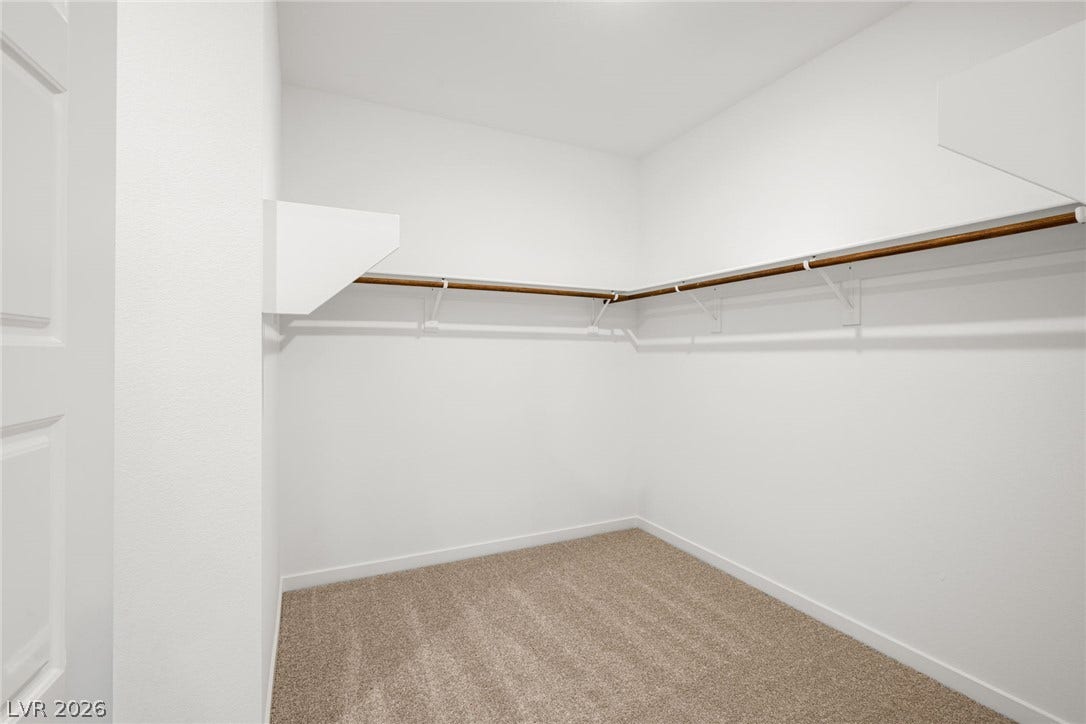 1429 Bianca Falls Drive, Henderson, NV 89011 A spacious walk-in closet includes built-in shelving, hanging rods, and carpet flooring.