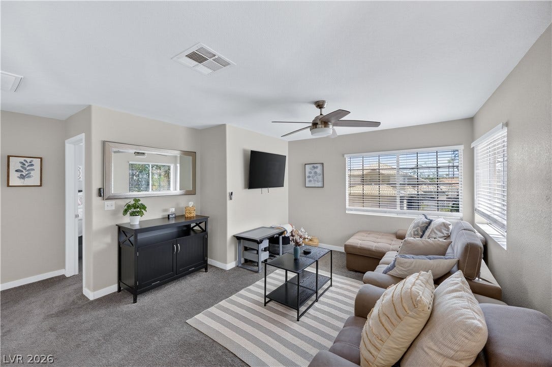 530 Rancho Del Mar Way, North Las Vegas, NV 89031 Natural light streams through multiple windows onto the comfortable carpeted flooring of this room.