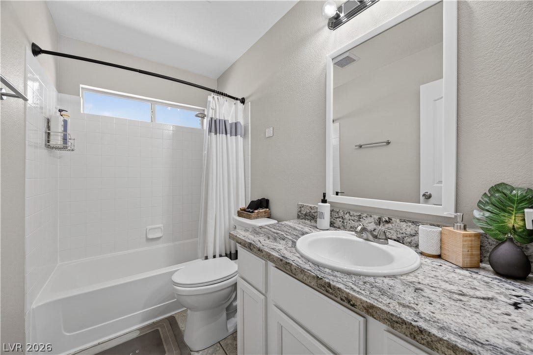 530 Rancho Del Mar Way, North Las Vegas, NV 89031 Granite counters and white tiled shower details elevate this modern guest bathroom.