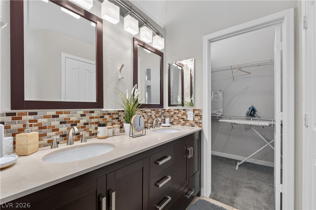 530 Rancho Del Mar Way, North Las Vegas, NV 89031 An elegant double vanity offers modern fixtures alongside a spacious walk-in closet.