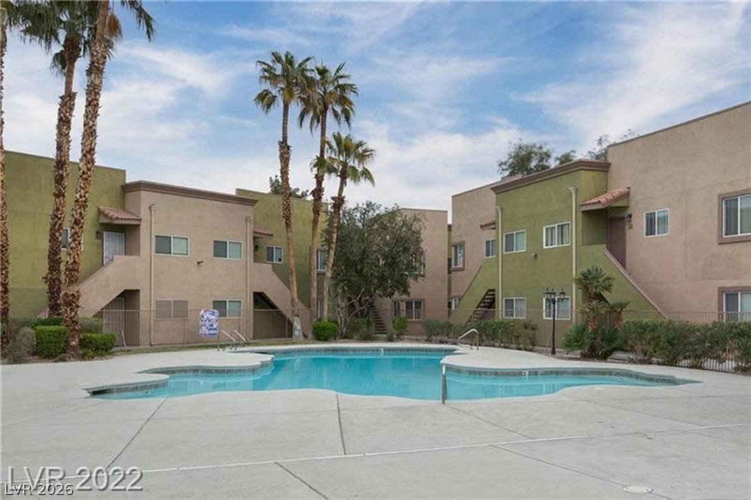 1814 N Decatur Boulevard, #202, Las Vegas, NV 89108 Mature palm trees frame a sparkling community swimming pool situated between multi-story residential buildings.