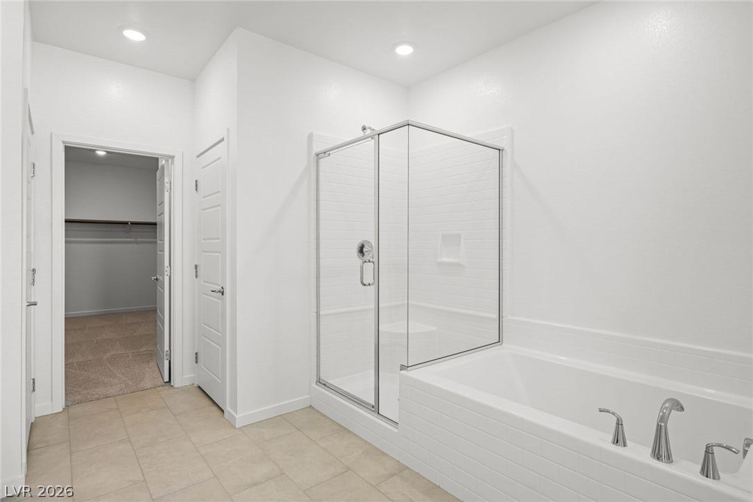 1480 Bianca Falls Drive, Henderson, NV 89011 A glass-enclosed shower and adjacent soaking tub sit on neutral tile flooring.