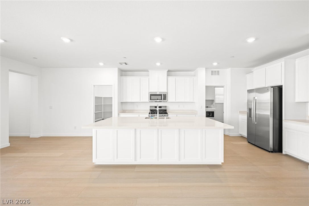 1480 Bianca Falls Drive, Henderson, NV 89011 Smooth wood floors anchor this expansive kitchen centered around a massive white prep island.
