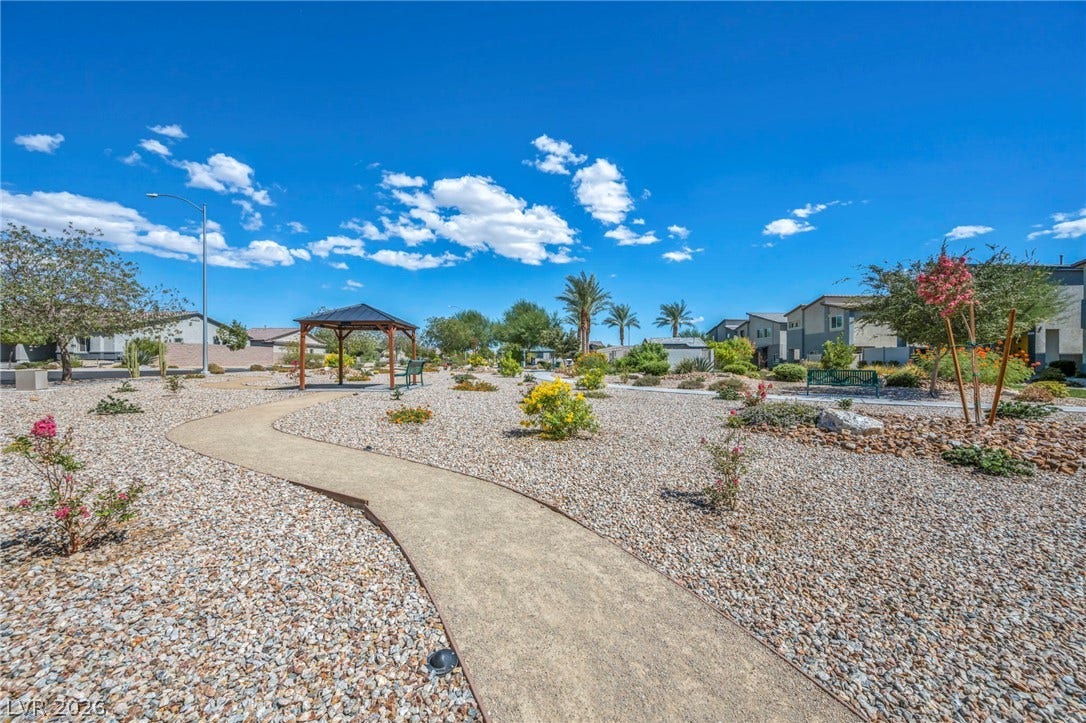 A winding paved walking path meanders through a beautifully landscaped desert common area.
