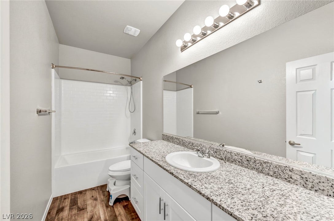 Polished granite countertops and classic wood-look flooring anchor this clean, functional bathroom.