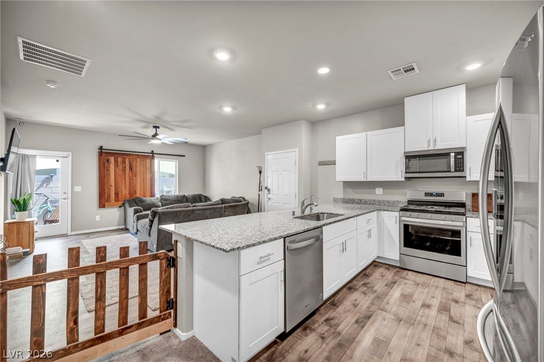 An open kitchen anchors the main living area, highlighted by granite countertops and wood-look flooring.