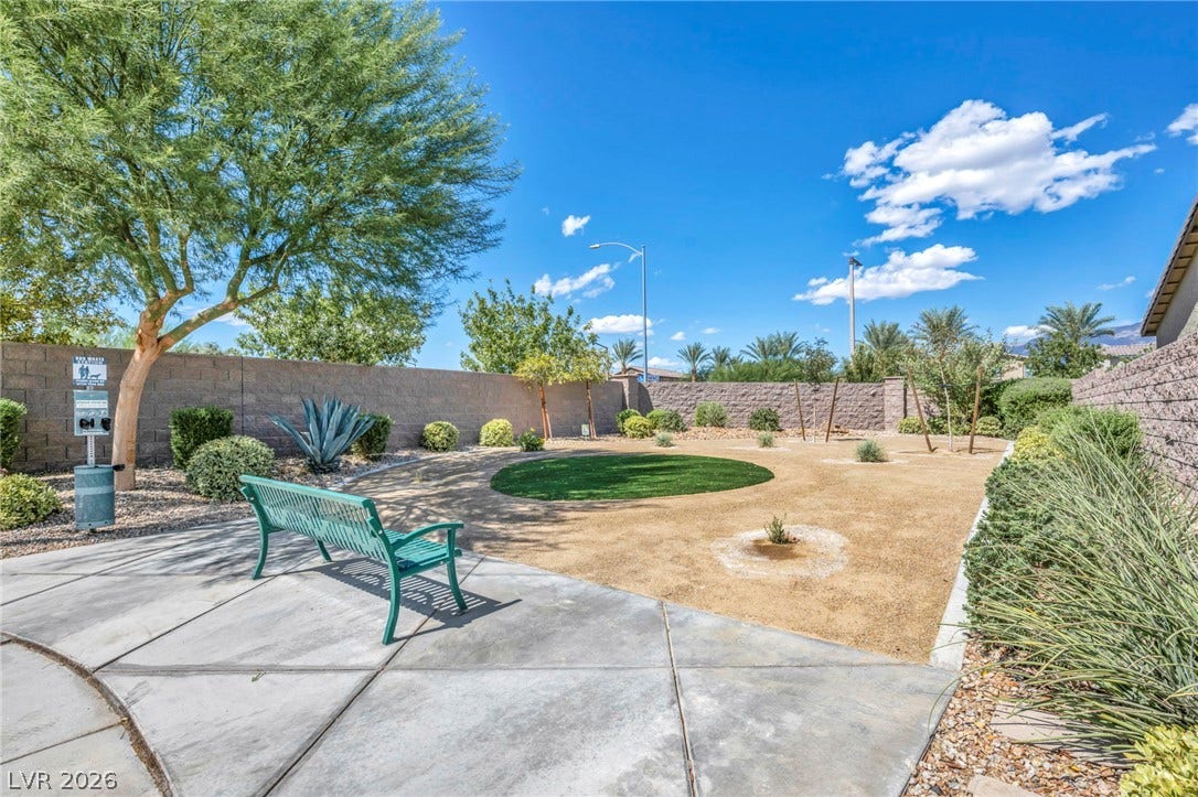 Manicured green spaces and paved pathways create a peaceful desert community park setting.