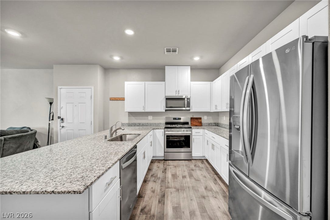 Polished granite countertops and modern stainless steel appliances define this streamlined, open kitchen space.