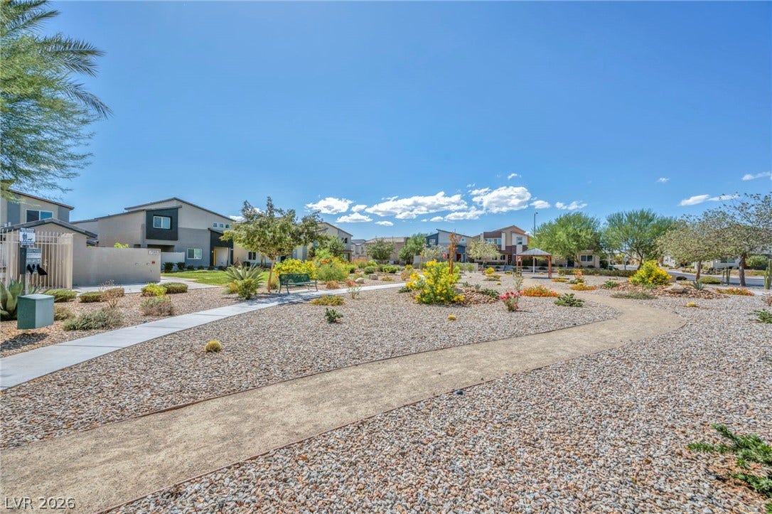 Meandering walkways wind through landscaped common areas under wide open desert skies.