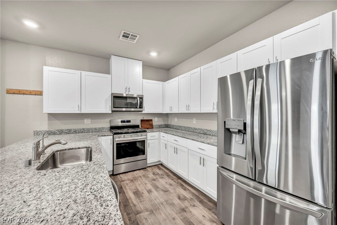 Gleaming granite countertops pair beautifully with white cabinetry and durable wood-look flooring.