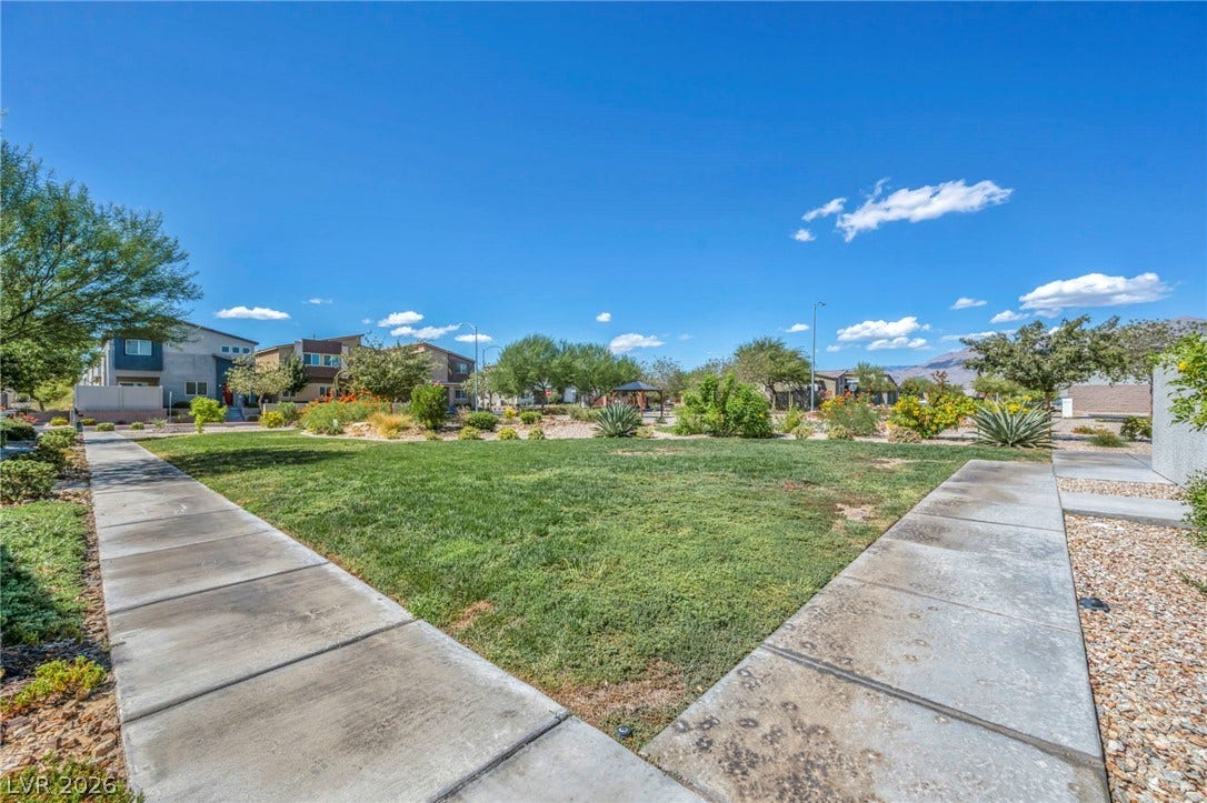 Concrete walkways border a lush green community lawn under bright desert skies.