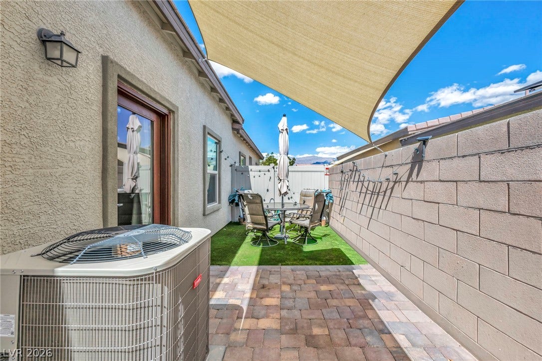 An inviting stone paver patio offers a private retreat beneath a protective shade sail.