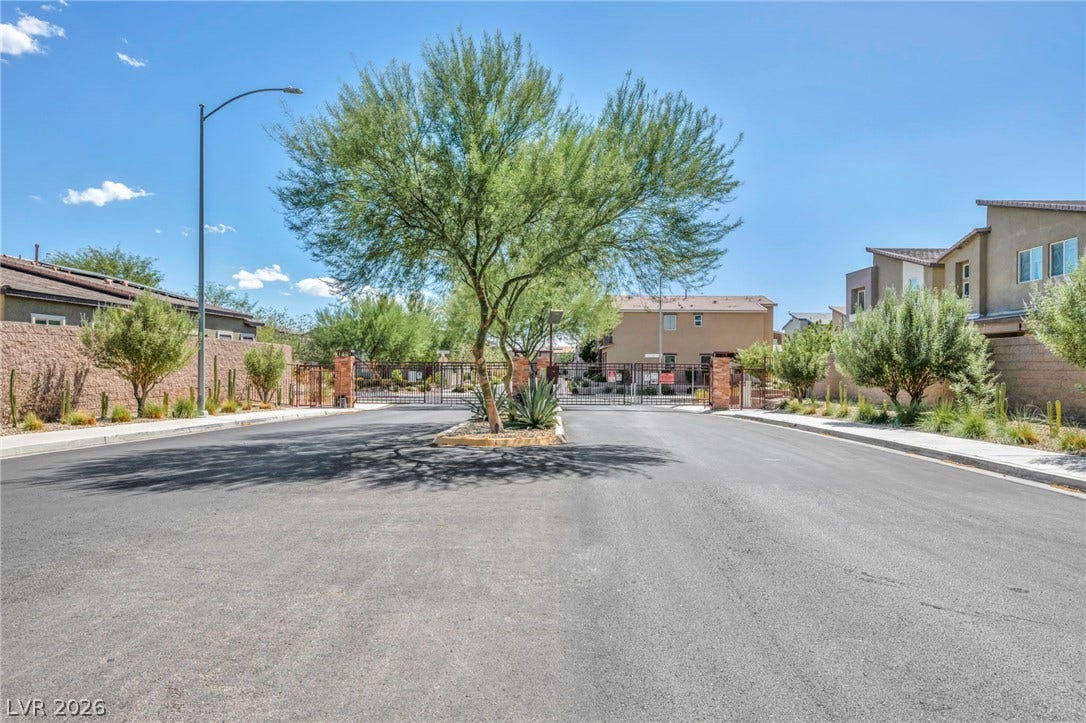 Secure gated entry welcomes residents home along paved streets lined with desert landscaping.