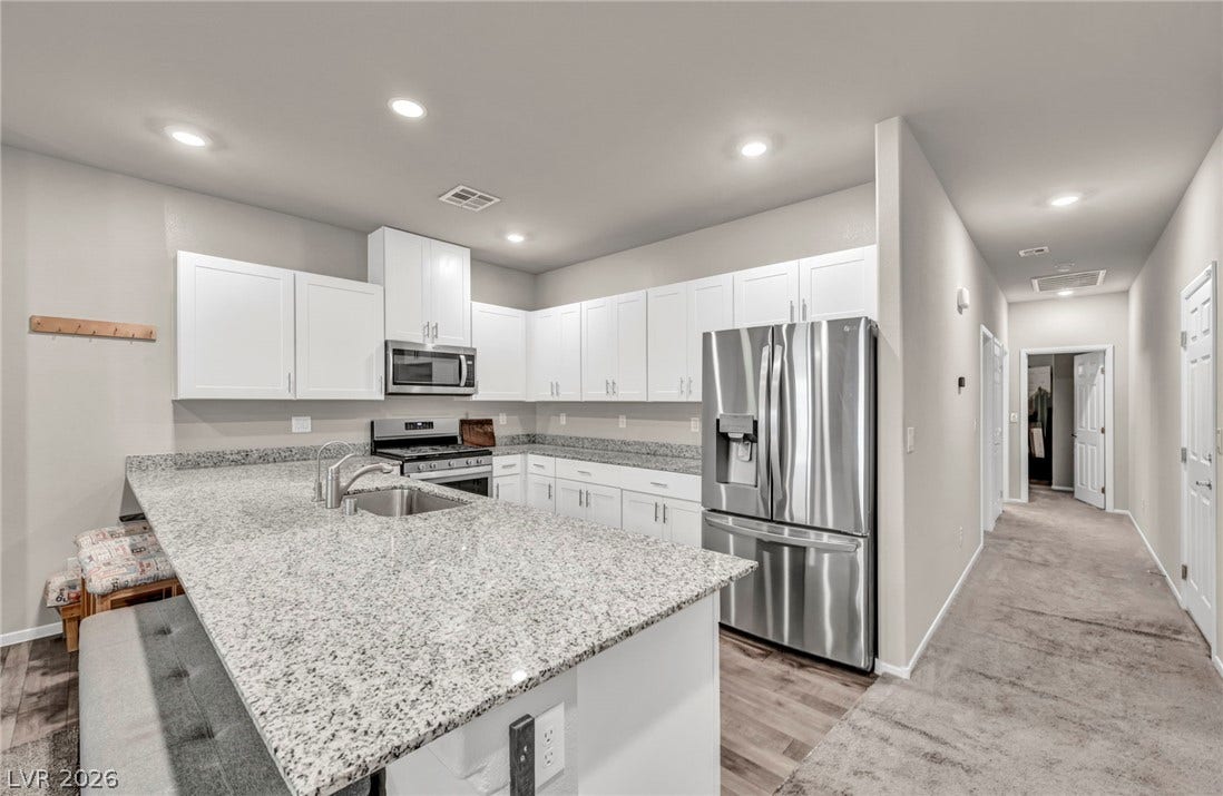 Polished stone countertops pair with white cabinetry in an airy culinary workspace.