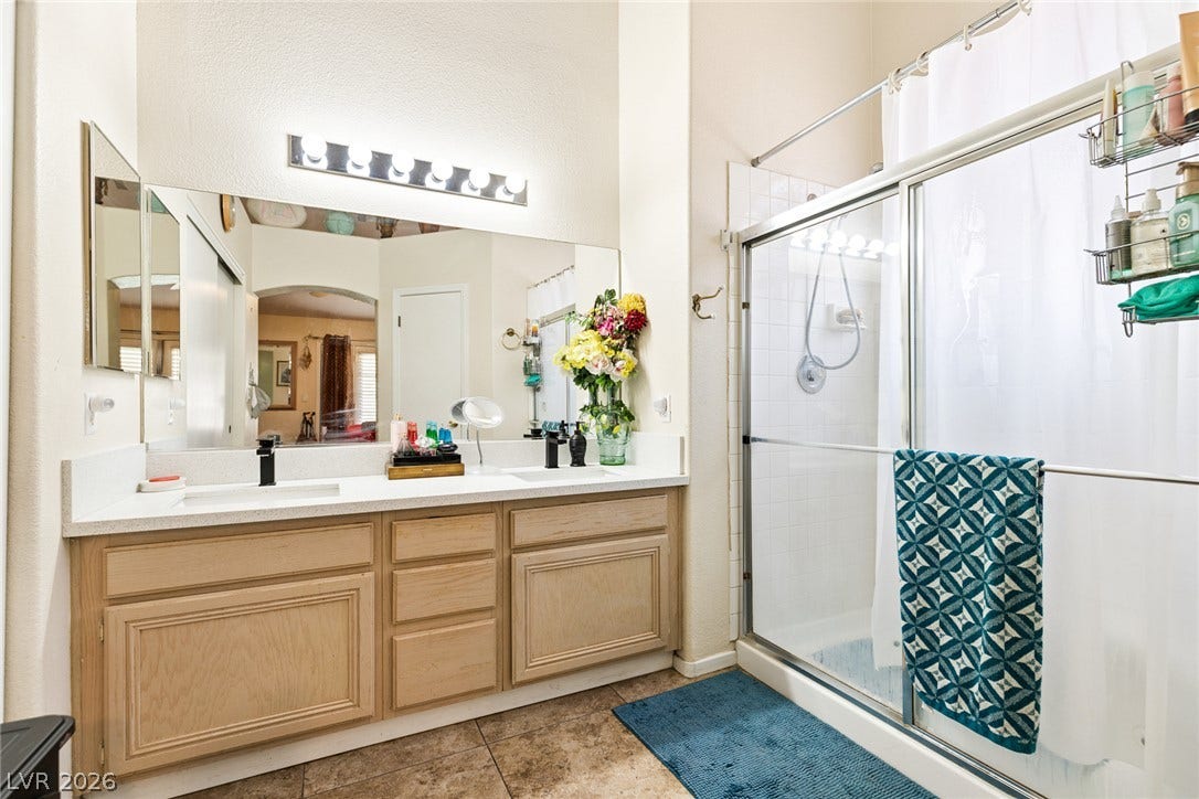 1747 Ashburn Drive, North Las Vegas, NV 89032 A spacious vanity with dual sinks anchors this bathroom featuring a glass-enclosed shower.
