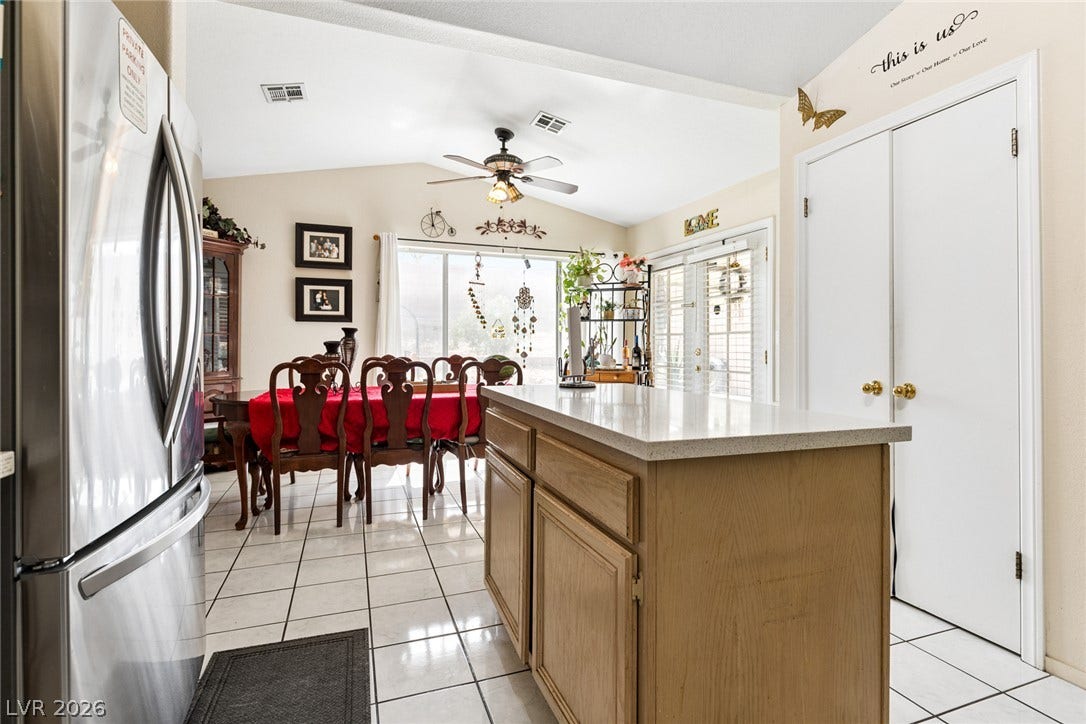 1747 Ashburn Drive, North Las Vegas, NV 89032 An open kitchen and dining area features vaulted ceilings, tile flooring, and a central island.