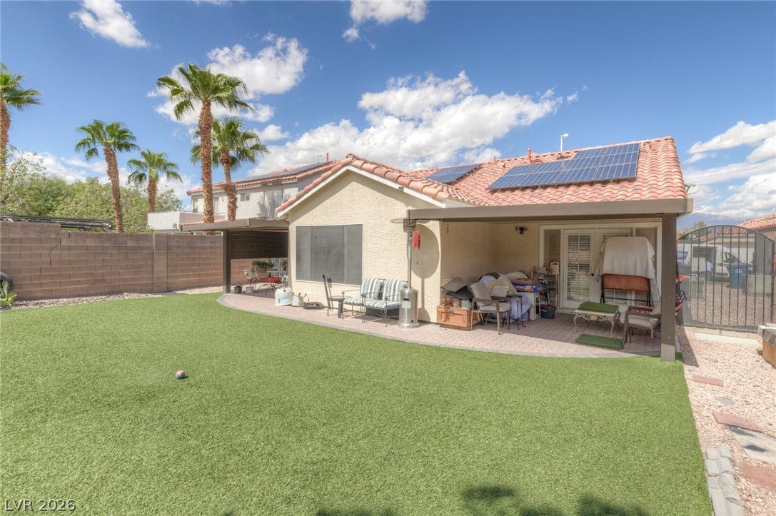 1747 Ashburn Drive, North Las Vegas, NV 89032 Sun-drenched backyard featuring a tiled roof, covered patio space, and manicured green lawn.
