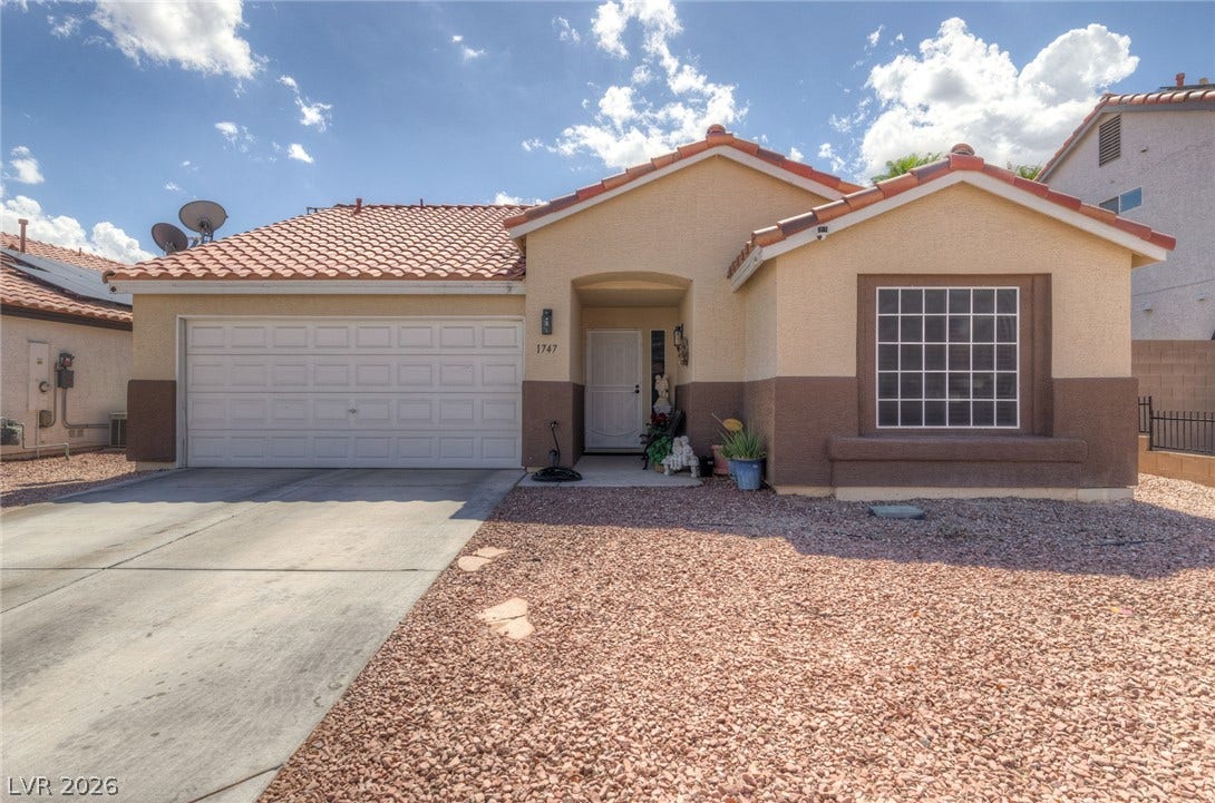 1747 Ashburn Drive, North Las Vegas, NV 89032 An inviting stucco exterior features a classic tile roof and an attached two-car garage.