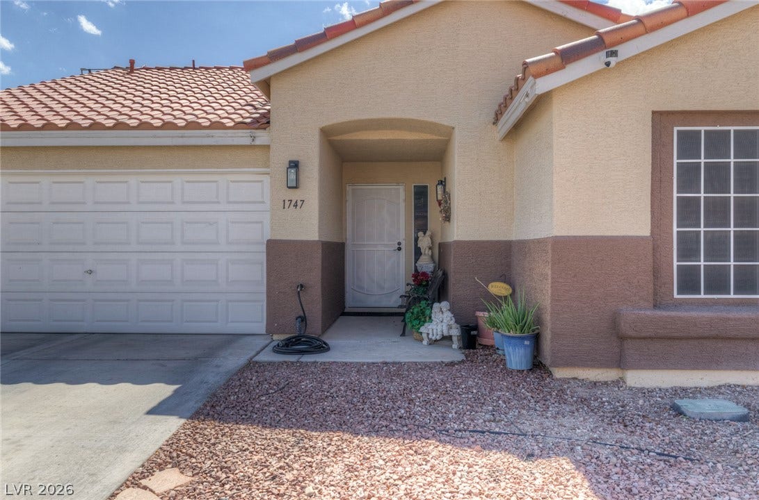 1747 Ashburn Drive, North Las Vegas, NV 89032 A welcoming covered entryway complements the classic stucco exterior and tile roof of this home.