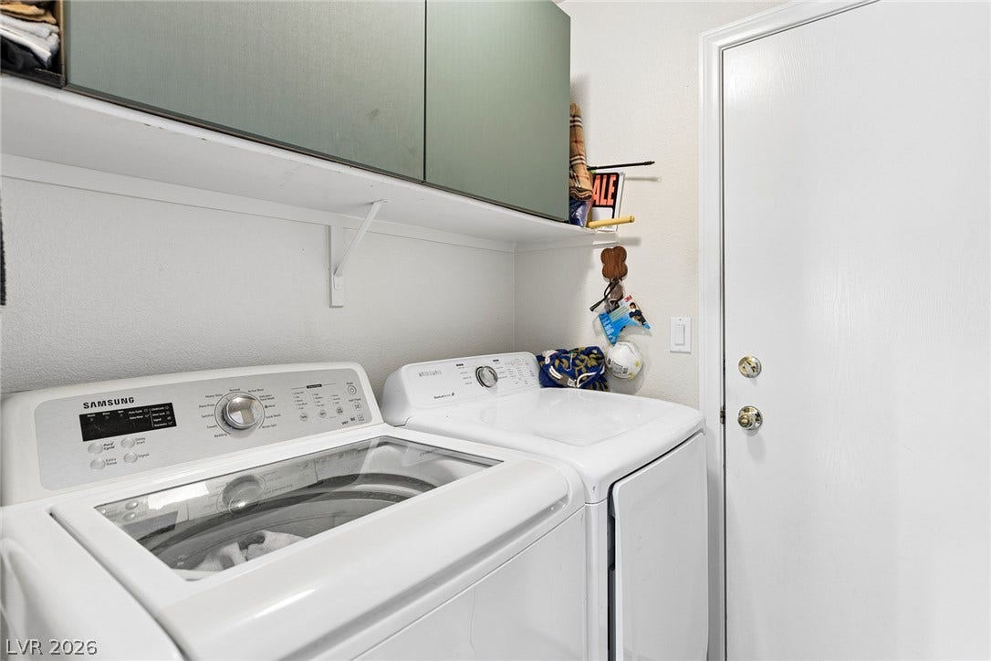1747 Ashburn Drive, North Las Vegas, NV 89032 An efficient laundry space includes overhead storage cabinetry alongside a functional service door.