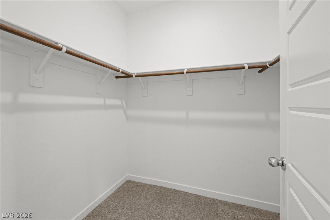8142 Gusty Brook Street, Las Vegas, NV 89113 Ample hanging rods and soft carpeting define this functional walk-in closet space.