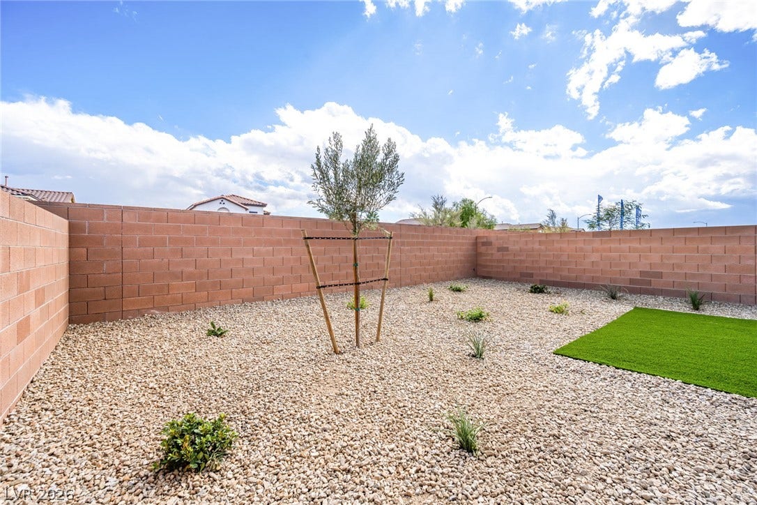 8142 Gusty Brook Street, Las Vegas, NV 89113 Secure block fencing encloses a low-maintenance gravel yard with desert plantings.