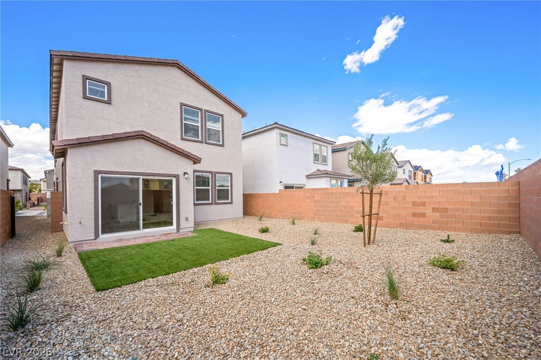 8142 Gusty Brook Street, Las Vegas, NV 89113 An enclosed backyard features gravel landscaping, a small lawn section, and a stone block wall.