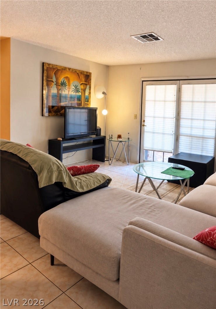 101 Luna Way, #242, Las Vegas, NV 89145 Glass sliding doors open to the outdoors, filling the tile-floored living area with natural light.