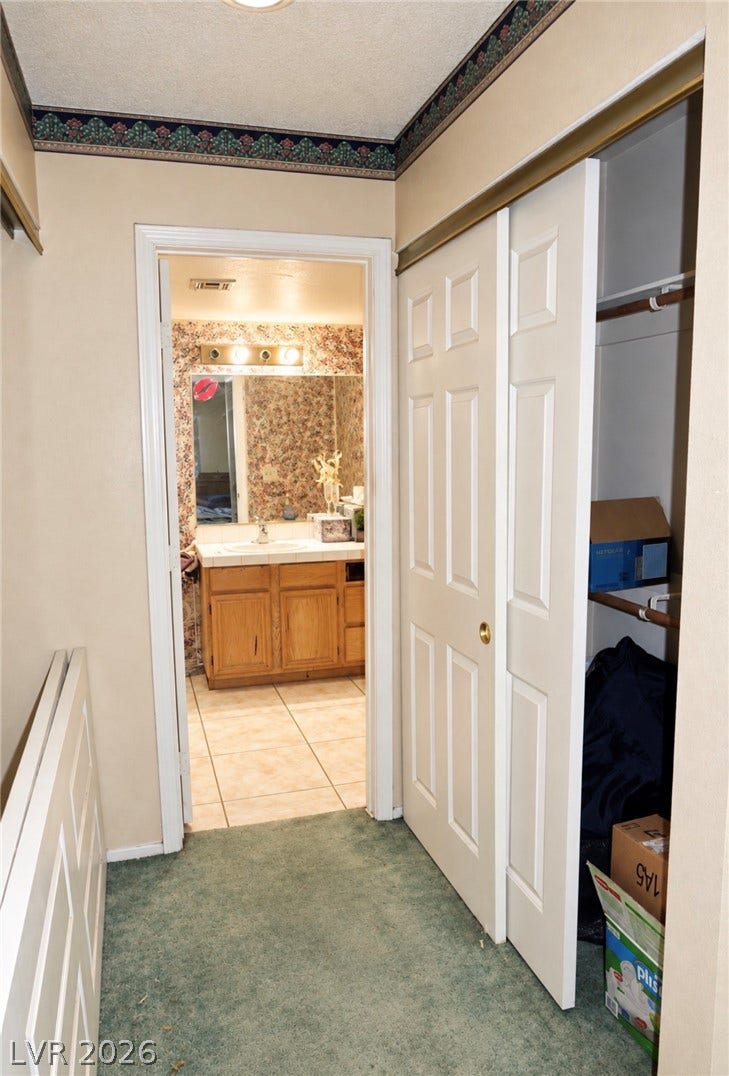 101 Luna Way, #242, Las Vegas, NV 89145 Carpeted hallway leads directly into a tiled bathroom featuring classic oak cabinetry.