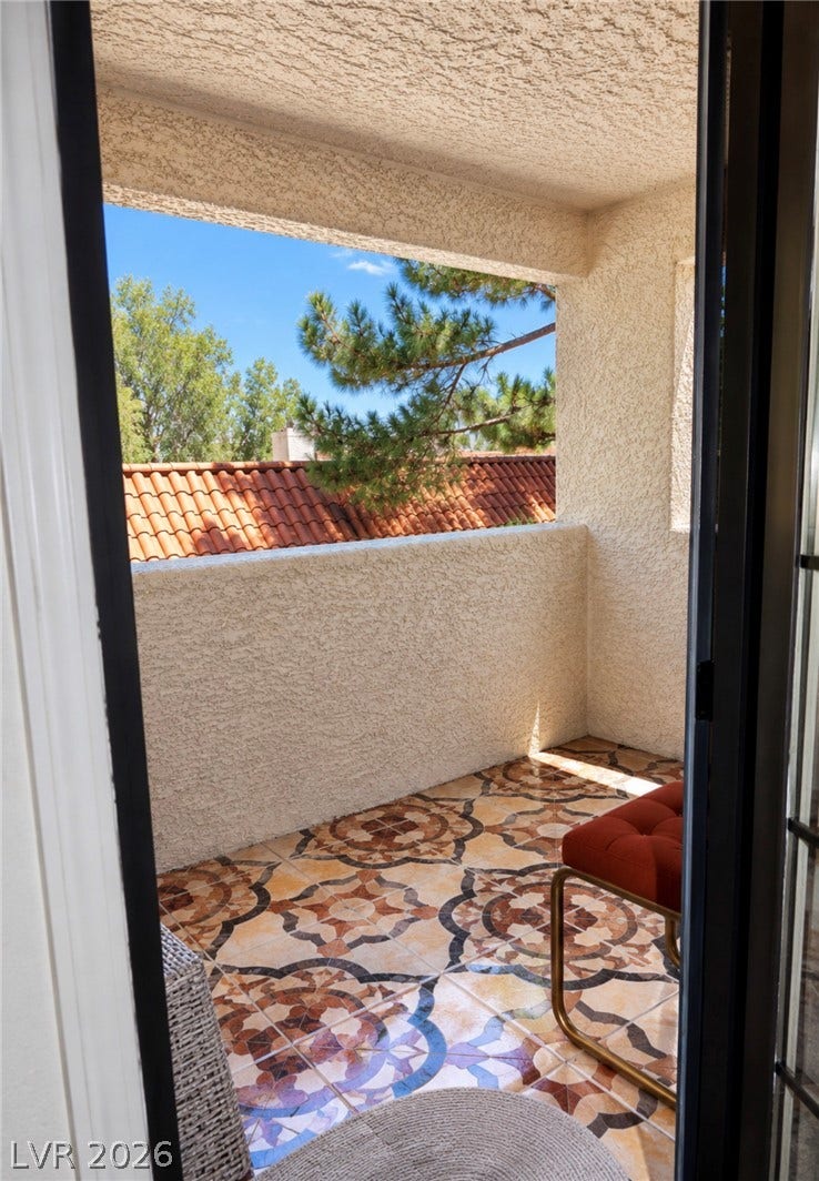 101 Luna Way, #242, Las Vegas, NV 89145 An inviting covered balcony features decorative tile flooring and views of mature trees.