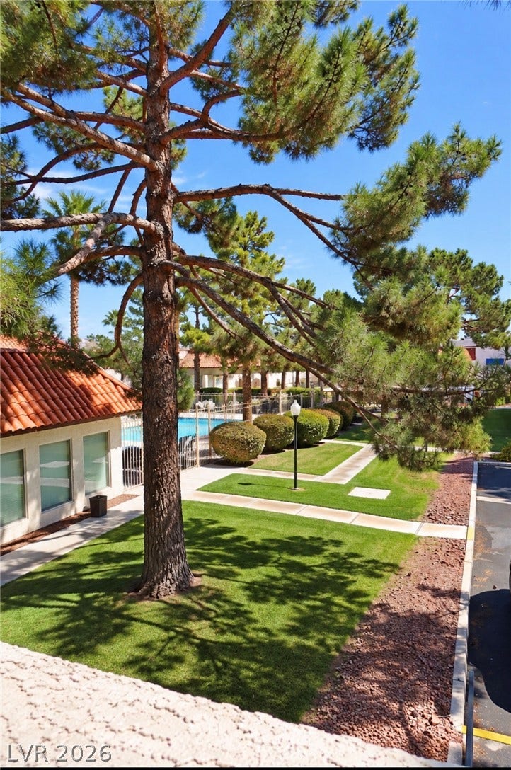 101 Luna Way, #242, Las Vegas, NV 89145 Manicured green lawns and mature pine trees line the pathways leading to the community pool.