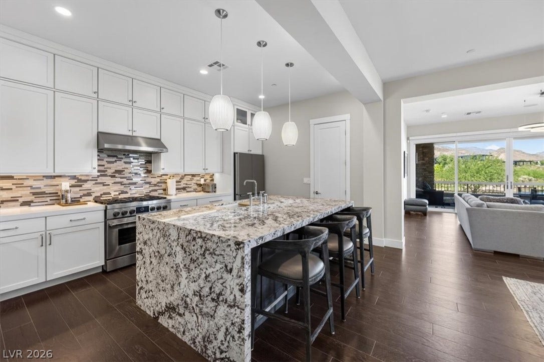 11280 Granite Ridge Drive, #1048, Las Vegas, NV 89135 Rich hardwood floors contrast beautifully with granite counters and white cabinetry in this open kitchen.