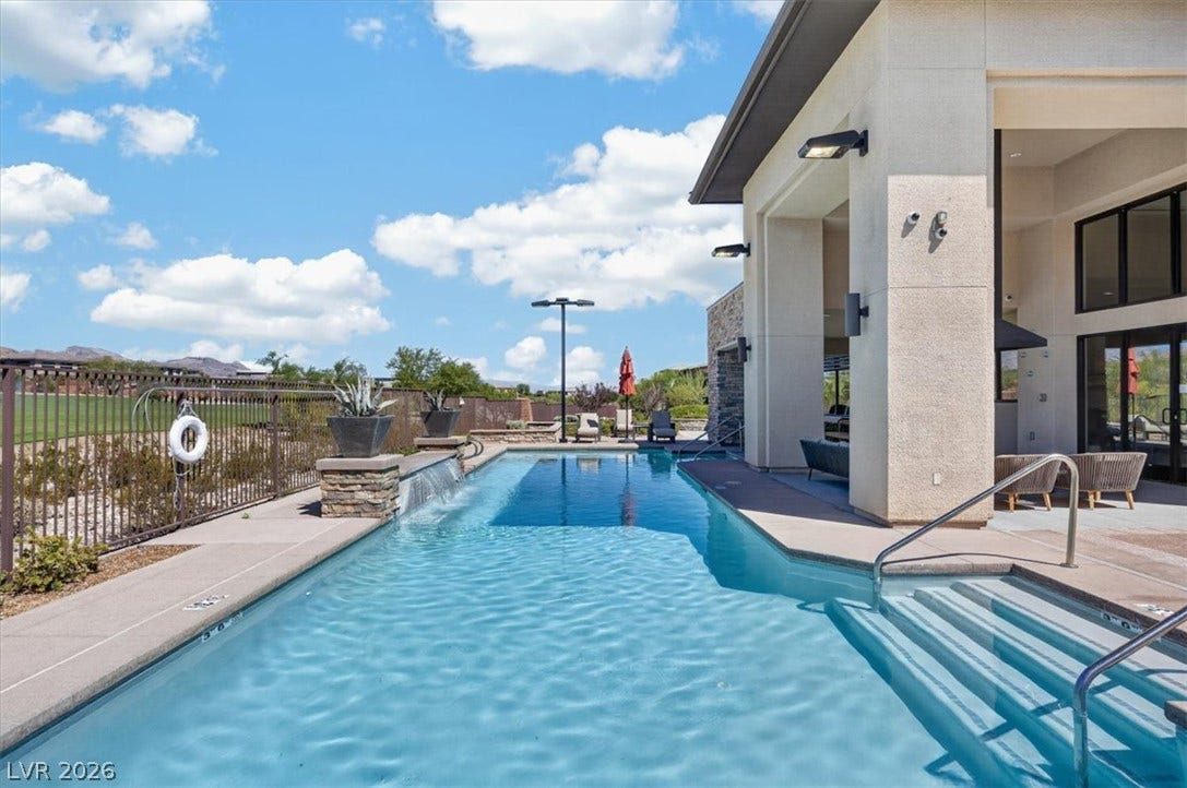 11280 Granite Ridge Drive, #1048, Las Vegas, NV 89135 An inviting swimming pool borders a modern structure under a bright desert sky.