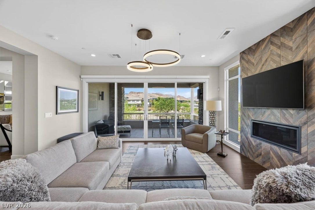 11280 Granite Ridge Drive, #1048, Las Vegas, NV 89135 Rich wood floors pair with a chevron tile fireplace wall and glass doors leading outdoors.