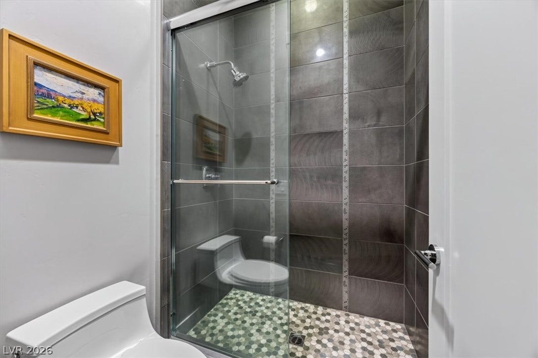 11280 Granite Ridge Drive, #1048, Las Vegas, NV 89135 Sleek contemporary tiling frames a glass-enclosed shower with mosaic stone floor accents.