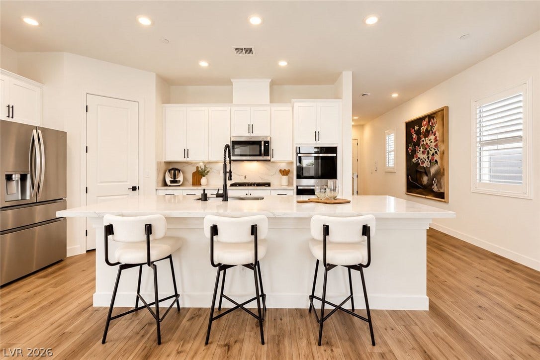Recessed lighting and warm wood flooring frame this elegant kitchen designed with a spacious central island.