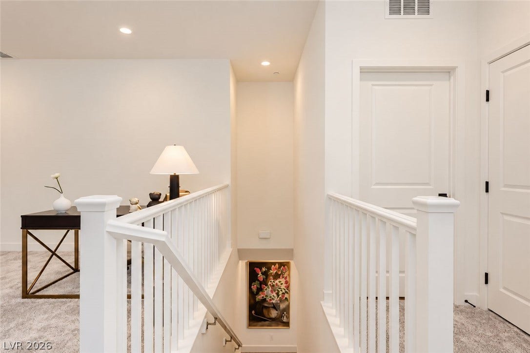 An upper-level landing connects clean architectural lines with neutral carpeting and classic white millwork.