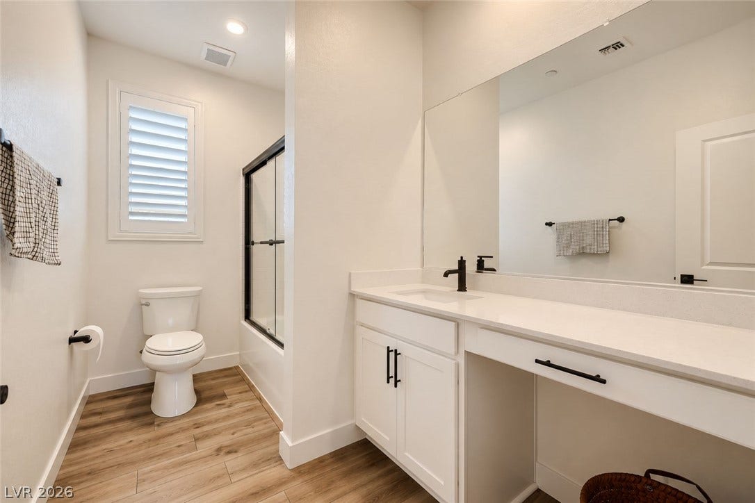 A spacious vanity with clean lines and recessed lighting defines this modern bathroom layout.