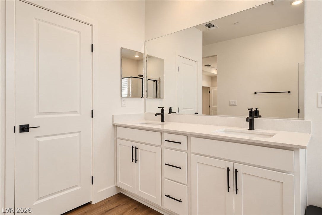 A spacious double vanity features clean white cabinetry and sleek modern hardware.
