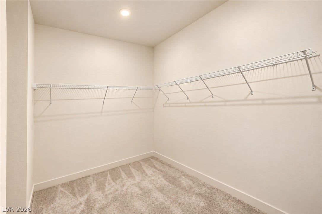 Ample wire shelving and plush carpeting maximize organization in this functional walk-in closet.