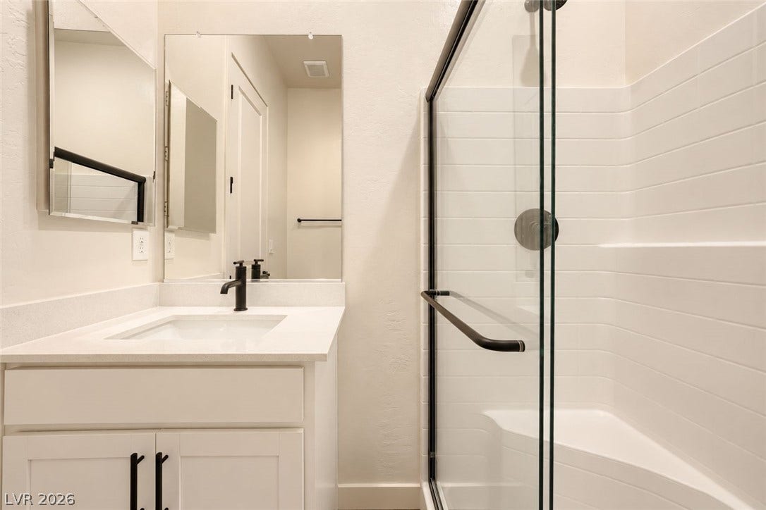A glass-enclosed walk-in shower pairs with a modern single vanity in this bathroom.