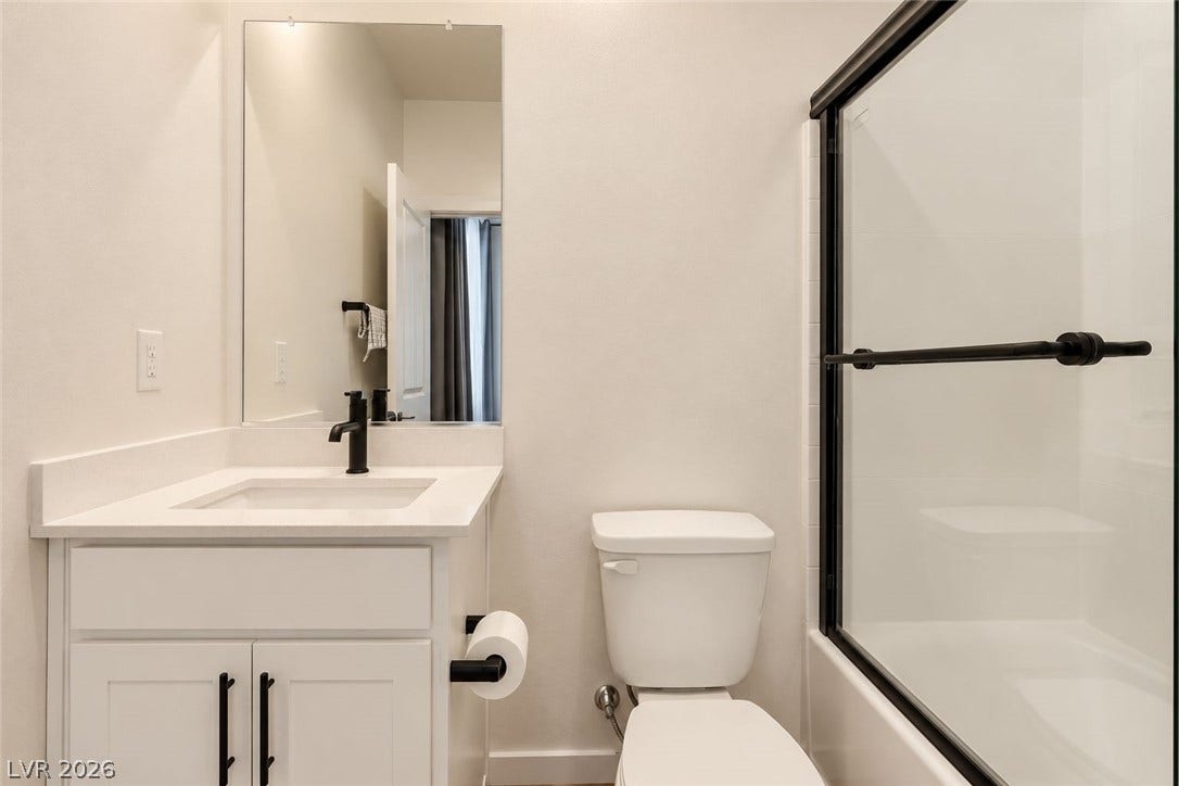 A modern single vanity and a glass-enclosed shower highlight this clean bathroom space.