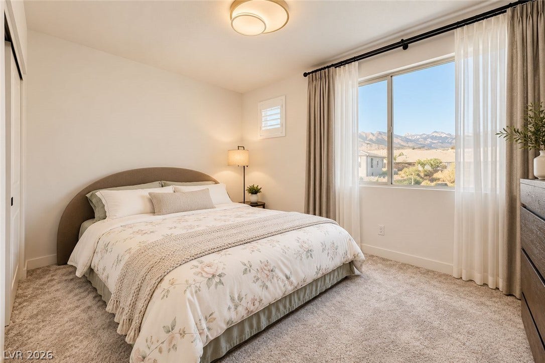 A spacious bedroom features soft carpet and wide windows framing scenic mountain views.