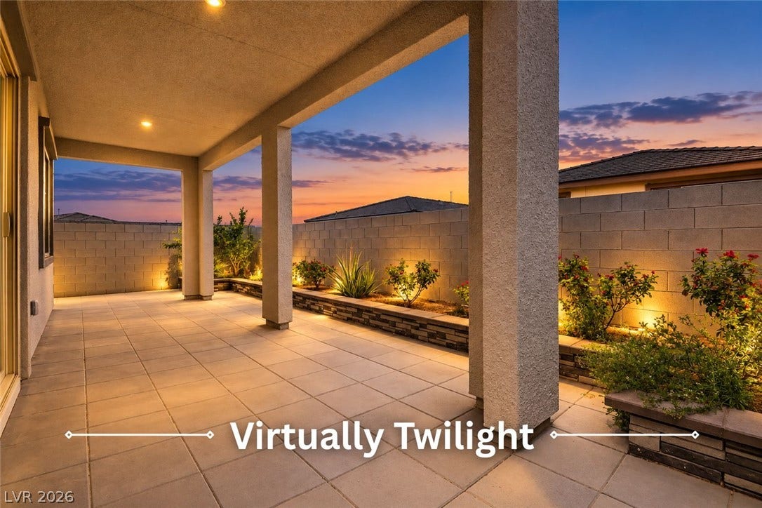 An inviting covered patio opens to a paved backyard enclosed by block fencing.