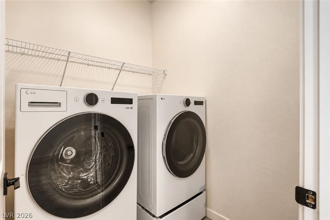 Functional laundry closet features neutral walls and a built-in wire storage shelf.