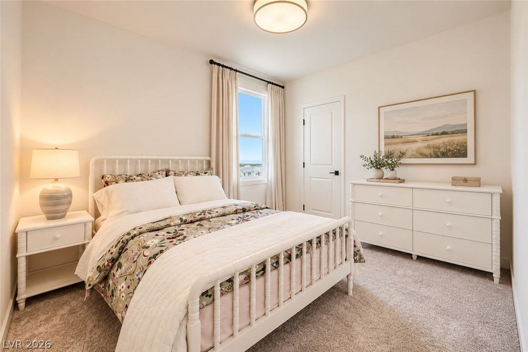 A tall window welcomes natural light across carpeted flooring and neutral-colored walls.